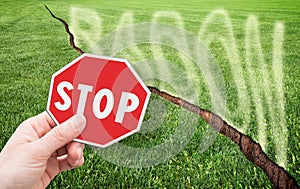A green mowed lawn with a diagonal crack with radon gas escaping - concept with stop sign