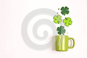 Green mug with four-leaf clover on white background. Copy space, top view