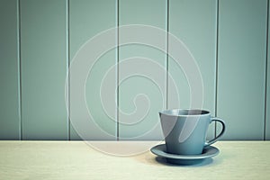 Green mug on wooden table over green background