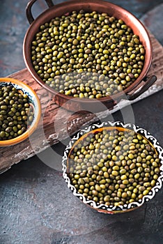 Green mung beans in bowls on wooden stand partial blur