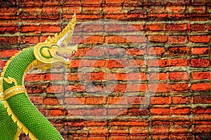 Green nagas statue on old brick wall