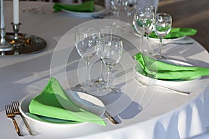 Green napkins lies on a white plate. Served table for the holiday.