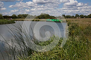 A green narrowboat on the Thames River at Farmoor in Oxfordshire in the UK