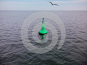 Green Navigational buoy in sea with clouds