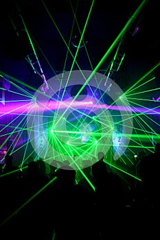 Green and neon laser lights in nightclub with dancers