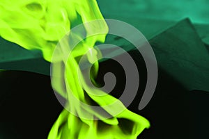 Green neon smoke on a dark background. Abstract flame texture