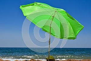 Green neon umbrella on the beach overlooking the blue ocean in the Summer