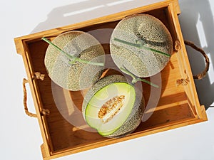 Green net melon fruit in wooden crate.