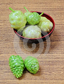 Green Noni or Morinda Citrifolia Fruits on Wooden Table