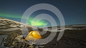Green Northern Lights over Glowing Tent in Khibiny Mountains. Russia. Time Lapse