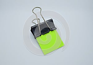 Green note paper with black binder clip. Binder clip and stack of green note paper