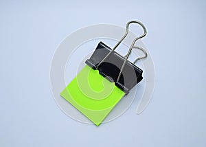 Green note paper with black binder clip. Binder clip and stack of green note paper