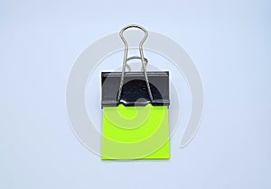 Green note paper with black binder clip. Binder clip and stack of green note paper