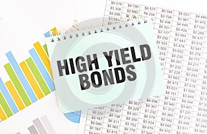 Green notepad on financial documentation. Text HIGH YELD BONDS. Business concept