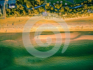 Green ocean water and yellow sandy beach.