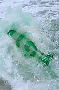 Green old bottle discarded and washed up on shore depicting environmental hazard