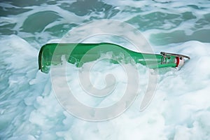 Green old bottle discarded and washed up on shore depicting environmental hazard