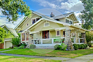 Green old craftsman style home with covered porch.