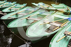 Green old empty boats with wooden oars on the lake closeup. Boat rental