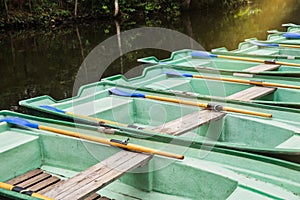 Green old empty boats with wooden oars on the lake closeup.Boat rental