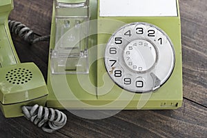 Green old-fashioned telephone on wooden background