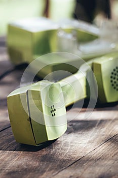 Green old-fashioned telephone on wooden background