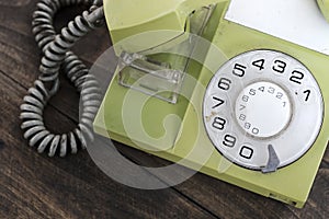 Green old-fashioned telephone on wooden background