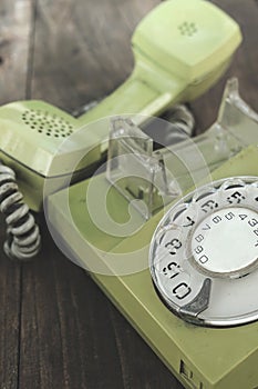 Green old-fashioned telephone on wooden background