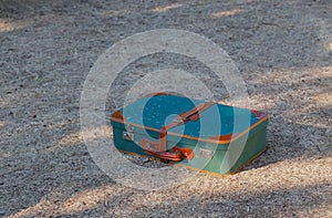 Green old suitcase on grass.