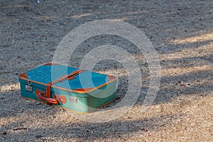 Green old suitcase on grass.