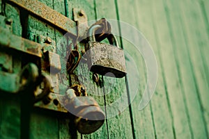 The green old wooden gate is closed with a rusty latch and a metal padlock. Old architectural details