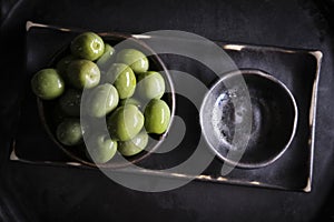 Green olives in a ceramic bowl on a wooden background.