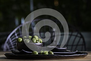 Green olives in a ceramic bowl on a wooden background.