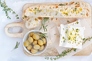 Green olives, feta cheese and fresh ciabata on a wooden board