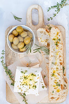 Green olives, feta cheese and fresh ciabata on a wooden board