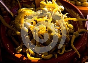 Green olives mix with paprika pepperoni in clay bowl in sunny day at the market in Spain