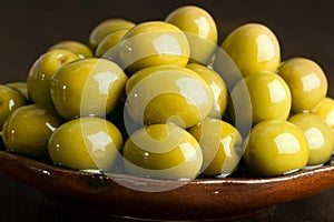 Green olives in oil stacked on a ceramic plate
