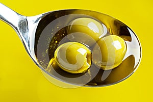 Green olives in spoon with olive oil
