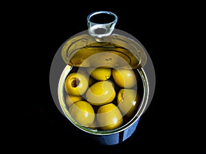 Green olives in a tin can on a black background