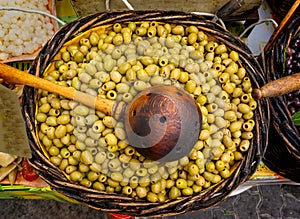 Green olives in a wooden bowl on an old table at an outside street market in France