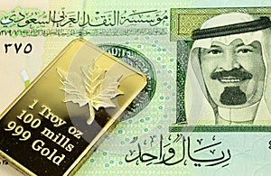 A green one Saudi riyal bank note with a gold bar in macro