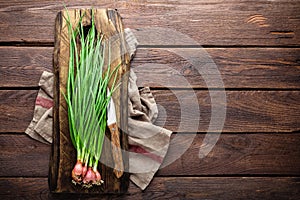 Green onion or scallion on wooden board, fresh spring chives