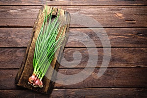 Green onion or scallion on wooden board, fresh spring chives