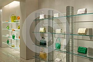 Green, orange and beige colors of fashionable handbags and purses on the shelves in a boutique store