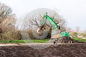 Green and orange excavator at construction site