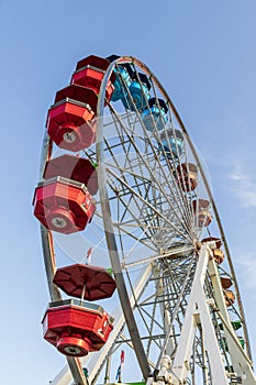 A green and orange Ferris wheel with red, white and blue flags and a gorgeous clear blue sky at the Carolina Beach Boardwalk
