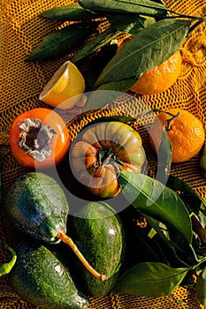 Green and orange fruits and vegetables  on woven yellow blanket