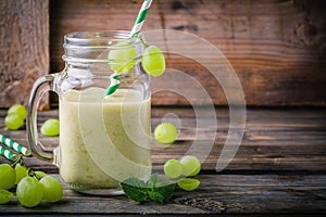 Green organic detox grape smoothie in glass mason jar on wooden background