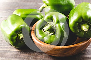 Green organic paprika on wooden bowl/Fresh green organic paprika on wooden bowl over dark background. Close up