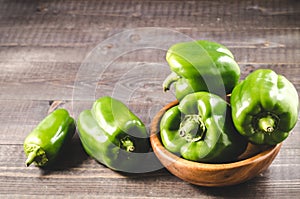 green organic paprika on wooden bowl /Fresh green organic paprika on wooden bowl over dark wooden background. Selective focus